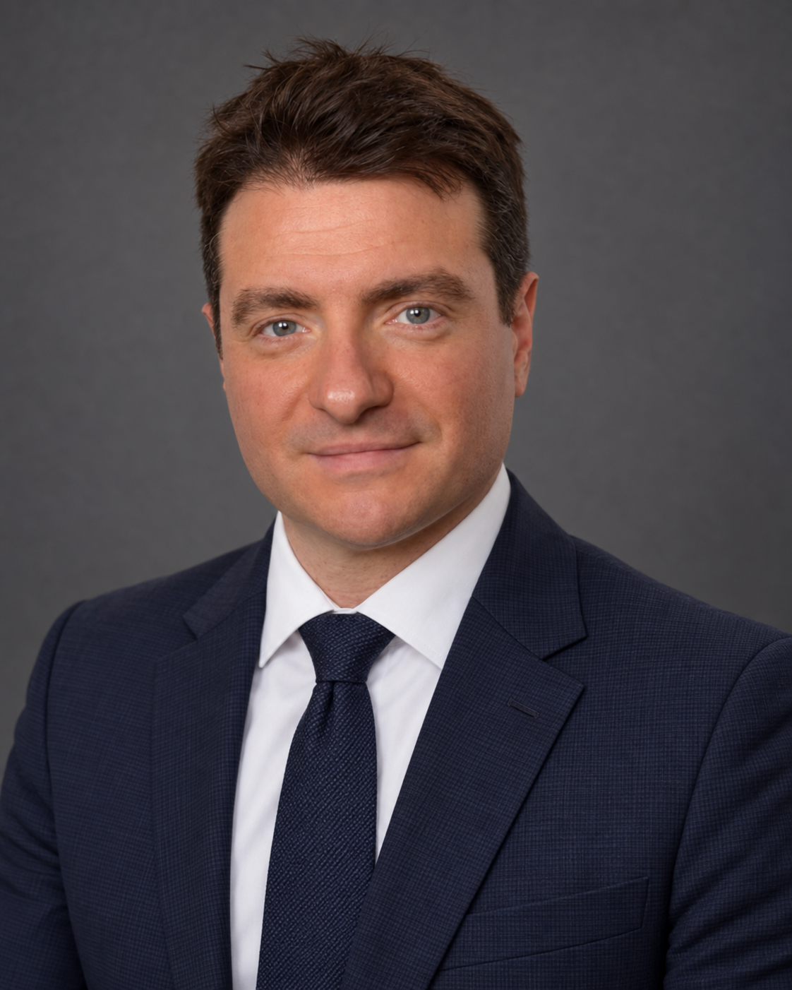 Maître David Dahan, avocat partenaire, en costume bleu marine sur fond gris